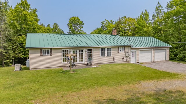 52A Judkins Rd, Harmony, ME 04942 - view of front facade with french doors, a chimney, a garage, a front lawn, and a standing seam roof