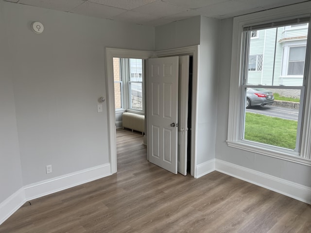 34 Birch St, Biddeford, ME 04005 - empty room featuring radiator, baseboards, wood finished floors, and a paneled ceiling