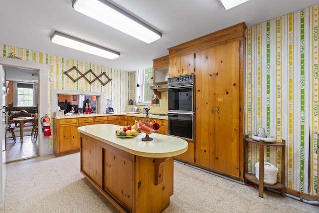 85 Friendship Rd, Waldoboro, ME 04572 - kitchen with wallpapered walls, light countertops, a center island, stovetop, and brown cabinets