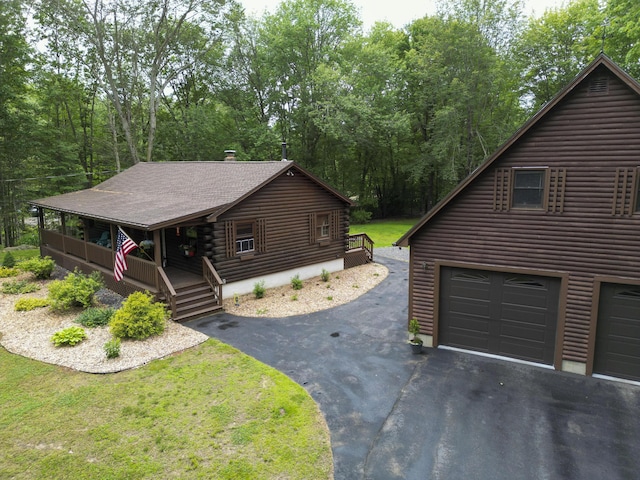 509 Upper Guinea Rd, Lebanon, ME 04027 - view of front of property with a porch, asphalt driveway, log exterior, and a garage