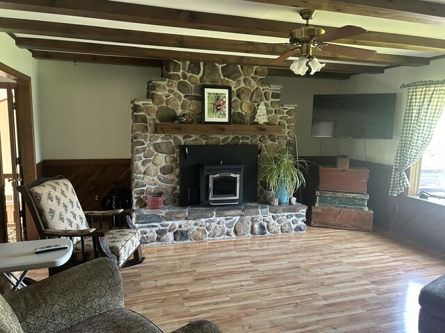 8 Camp Rd, Hartford, ME 04220 - living area featuring beam ceiling, wood finished floors, ceiling fan, a wainscoted wall, and a wood stove