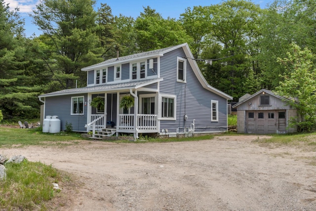 133 Middlesex Rd, Topsham, ME 04086 - view of front of house with a porch, an outdoor structure, a detached garage, driveway, and view of scattered trees