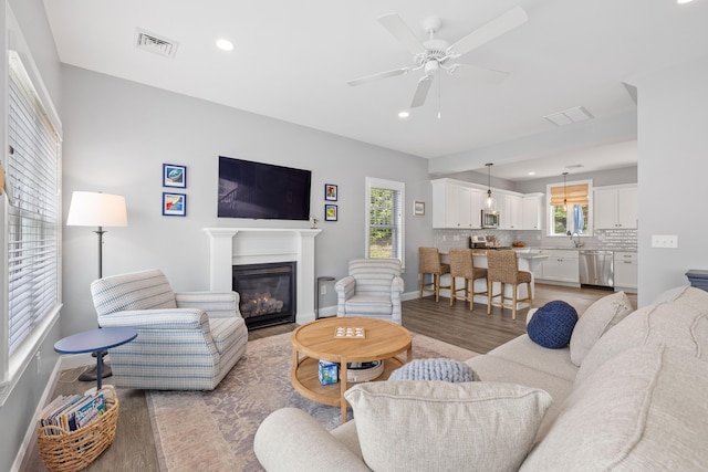 46 Patriot Way Unit 135, Arundel, ME 04046 - living area featuring a glass covered fireplace, light wood-style flooring, baseboards, recessed lighting, and a ceiling fan