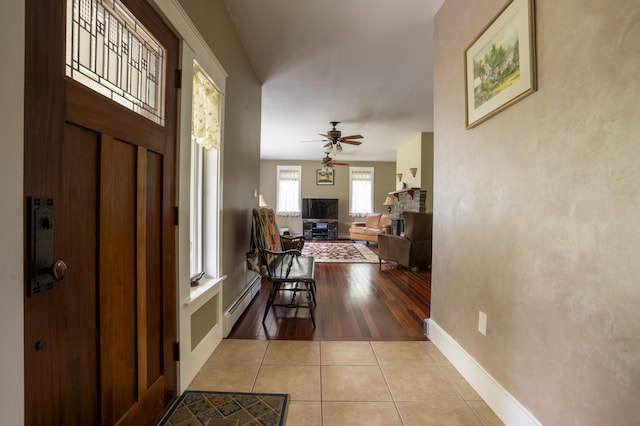 15 Brookview Dr, Bucksport, ME 04416 - entryway with a baseboard heating unit, a fireplace, light tile patterned flooring, baseboards, and ceiling fan