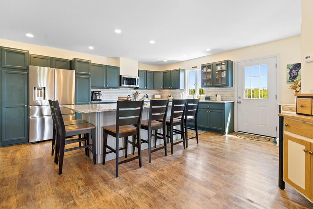 18 Fox Meade Ln, Searsmont, ME 04973 - kitchen featuring stainless steel appliances, a breakfast bar, decorative backsplash, green cabinetry, and glass insert cabinets