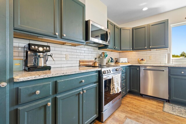 18 Fox Meade Ln, Searsmont, ME 04973 - kitchen with appliances with stainless steel finishes, light wood-style flooring, tasteful backsplash, and light stone counters