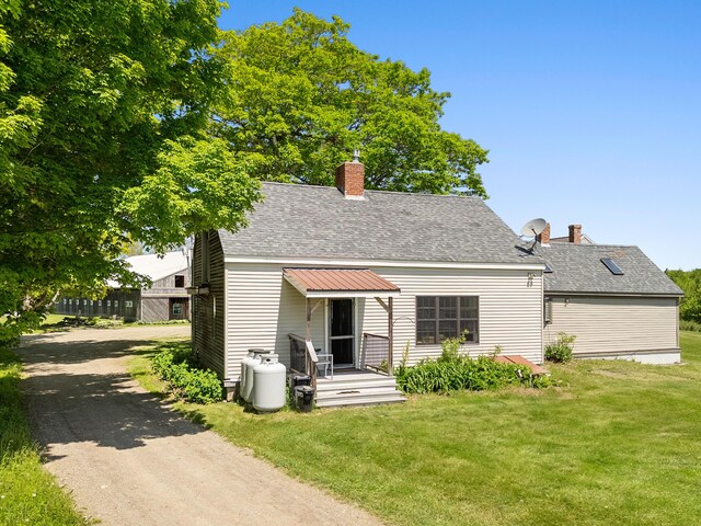 18 Fox Meade Ln, Searsmont, ME 04973 - back of property featuring a chimney, a lawn, roof with shingles, and asphalt driveway