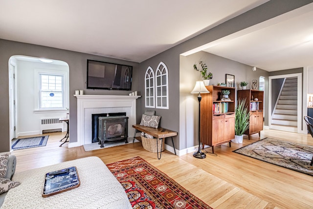 115 Caleb St, Portland, ME 04102 - living room featuring radiator, stairway, wood finished floors, and a wood stove