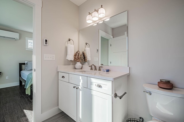 19 Efficiency Way, Bridgton, ME 04009 - bathroom featuring an AC wall unit, vanity, wood finished floors, connected bathroom, and toilet