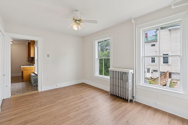20 Green St, Winthrop, ME 04364 - spare room featuring light wood-style floors, radiator, baseboards, a ceiling fan, and a sink