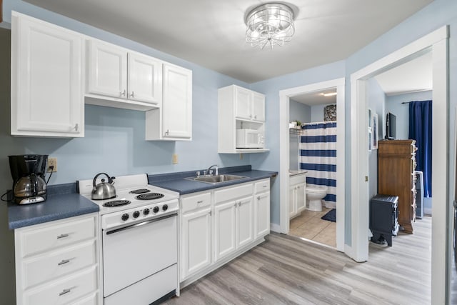 1139 Post Rd Unit 102, Wells, ME 04090 - kitchen featuring white appliances, a sink, dark countertops, and white cabinets