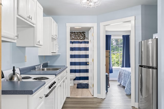 1139 Post Rd Unit 102, Wells, ME 04090 - kitchen featuring freestanding refrigerator, a sink, white cabinetry, stove, and dark countertops