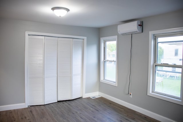 2 Watson Ave, Houlton, ME 04730 - unfurnished bedroom with an AC wall unit, baseboards, dark wood-style flooring, and a closet