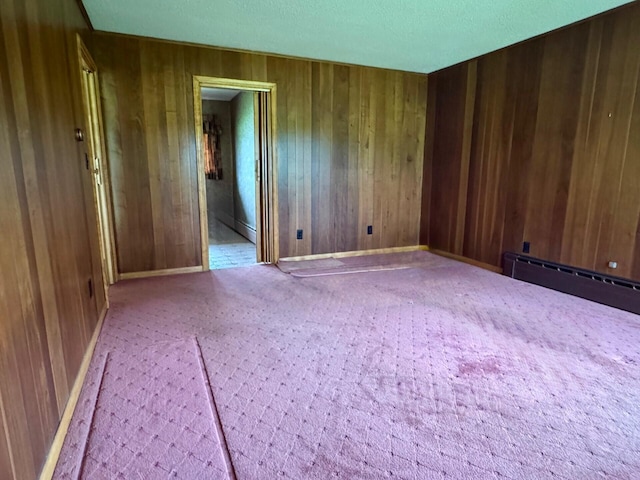 02 Rogers St, Houlton, ME 04730 - carpeted empty room with wood walls, a baseboard radiator, and baseboards