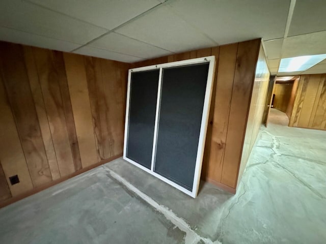 02 Rogers St, Houlton, ME 04730 - unfurnished bedroom with wood walls, concrete flooring, a paneled ceiling, and a closet