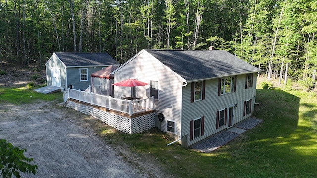 50 NW River Rd, Sebago, ME 04029 - view of side of property with a wooden deck, a forest view, a shingled roof, and a lawn