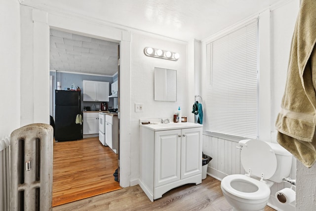 82 Winter St, Portland, ME 04102 - bathroom featuring wood finished floors, ornamental molding, vanity, radiator heating unit, and toilet