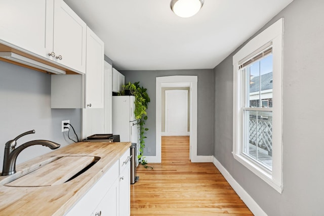 82 Winter St, Portland, ME 04102 - kitchen featuring a sink, light wood finished floors, white cabinetry, baseboards, and freestanding refrigerator