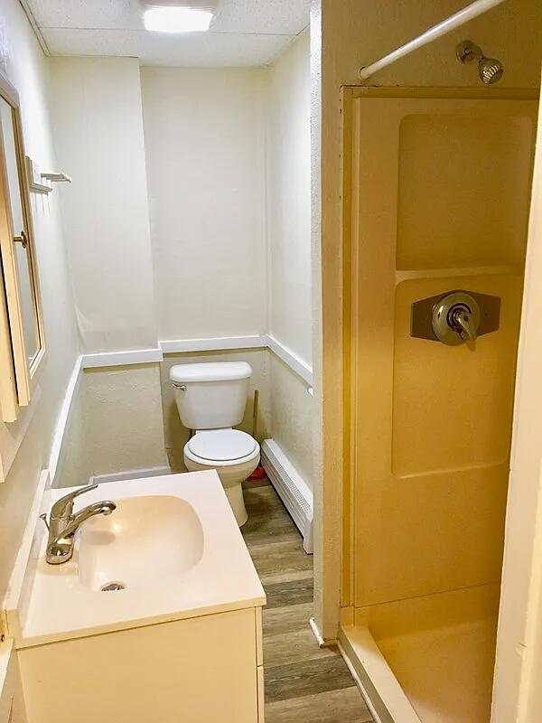 82 Winter St, Portland, ME 04102 - full bath featuring a shower stall, wood finished floors, toilet, vanity, and baseboard heating