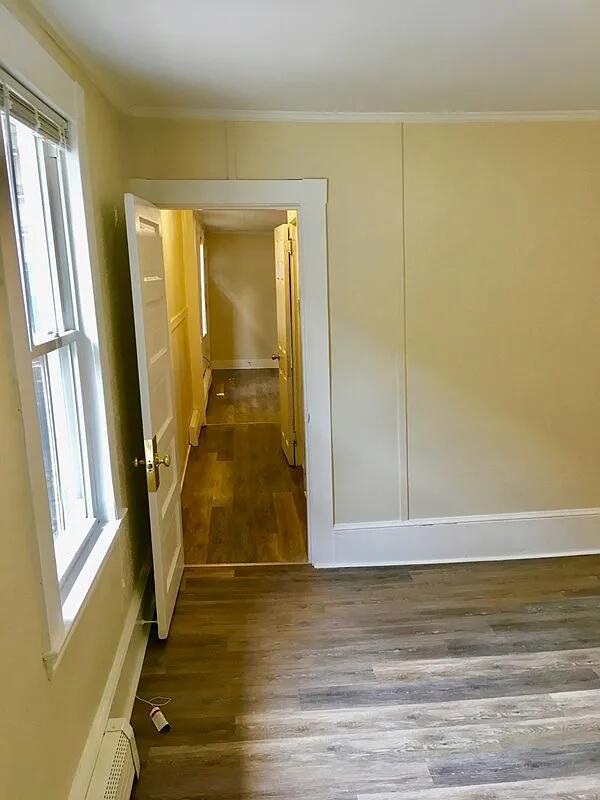 82 Winter St, Portland, ME 04102 - empty room featuring wood finished floors, crown molding, baseboards, and baseboard heating