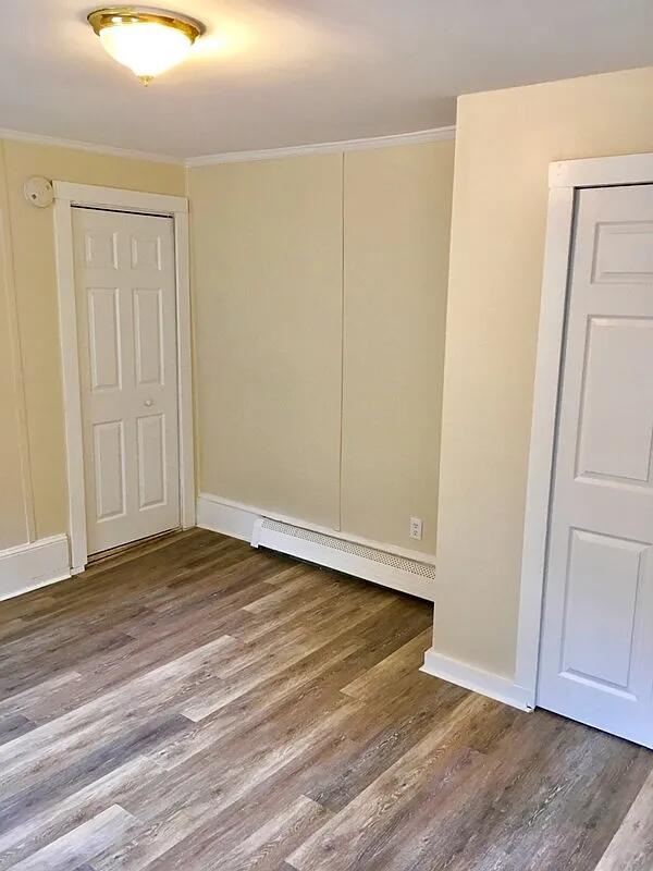 82 Winter St, Portland, ME 04102 - unfurnished bedroom featuring ornamental molding, a baseboard radiator, wood finished floors, and baseboards