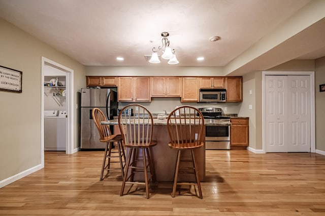 170 E Grand Ave Unit 1, Old Orchard Beach, ME 04064 - kitchen featuring stainless steel appliances, light wood-style floors, a breakfast bar, a center island with sink, and baseboards