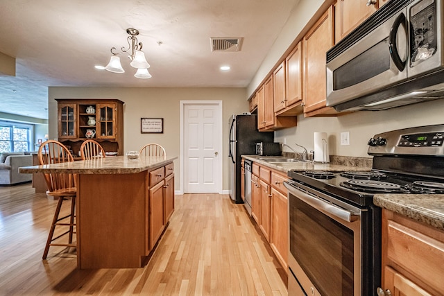 170 E Grand Ave Unit 1, Old Orchard Beach, ME 04064 - kitchen with appliances with stainless steel finishes, a kitchen breakfast bar, a sink, a kitchen island, and light wood finished floors