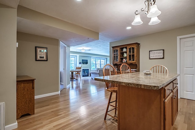 170 E Grand Ave Unit 1, Old Orchard Beach, ME 04064 - kitchen with a breakfast bar area, brown cabinets, light wood finished floors, open floor plan, and baseboards