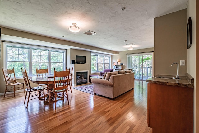 170 E Grand Ave Unit 1, Old Orchard Beach, ME 04064 - dining room featuring light wood finished floors, a glass covered fireplace, and a textured ceiling