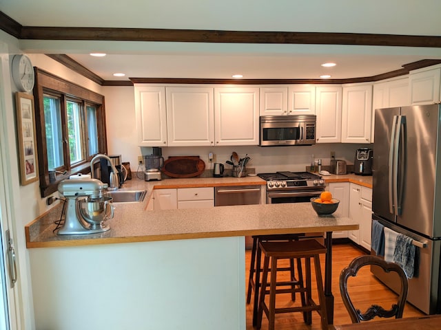 630 Youngs Ridge Rd, Acton, ME 04001 - kitchen with stainless steel appliances, a peninsula, white cabinetry, ornamental molding, and recessed lighting