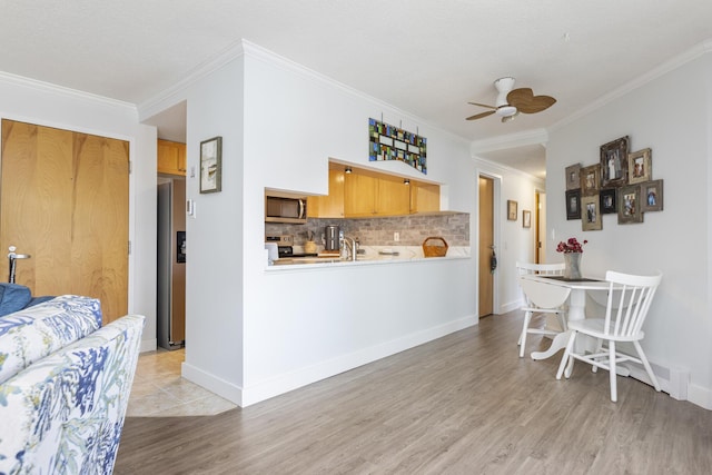 219 E Grand Ave Unit 3C, Old Orchard Beach, ME 04064 - kitchen with stainless steel microwave, light wood finished floors, a ceiling fan, range, and backsplash