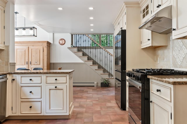 106 Fieldstone Estates Rd, York, ME 03909 - kitchen with gas stove, baseboard heating, under cabinet range hood, recessed lighting, and a wainscoted wall