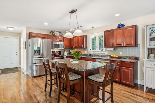 3 Bradfield Way, Kennebunk, ME 04043 - kitchen with appliances with stainless steel finishes, a breakfast bar, light wood-type flooring, decorative light fixtures, and a center island