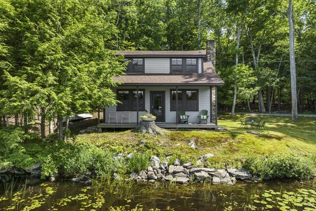 36 Cove Ln, Damariscotta, ME 04543 - view of front facade featuring a chimney, roof with shingles, a front yard, and a wooden deck