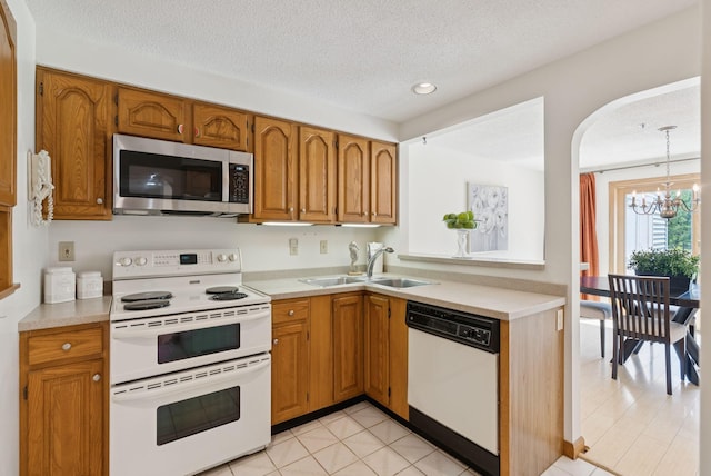 44 Meadowbrook Dr Unit 4, Gorham, ME 04038 - kitchen featuring white appliances, a sink, a chandelier, light countertops, and brown cabinets