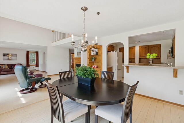 44 Meadowbrook Dr Unit 4, Gorham, ME 04038 - dining space featuring arched walkways, light wood finished floors, a chandelier, and baseboards