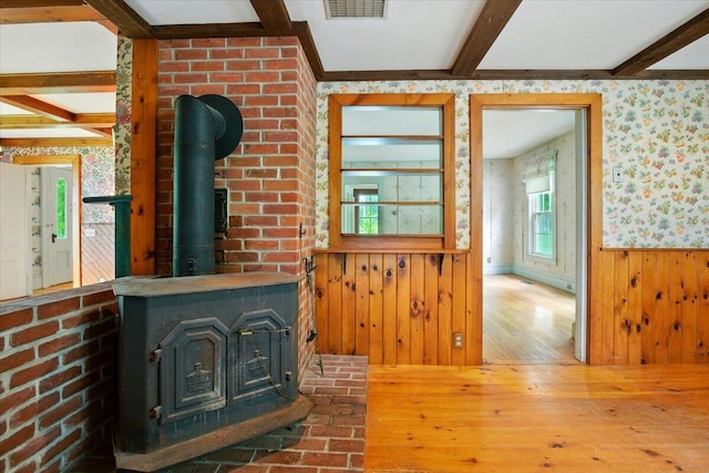 1835 Main St, Fayette, ME 04349 - unfurnished living room with beam ceiling, wallpapered walls, hardwood / wood-style flooring, a wood stove, and wainscoting