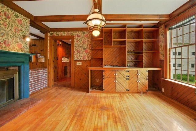 1835 Main St, Fayette, ME 04349 - unfurnished living room with wood-type flooring, wooden walls, beam ceiling, a brick fireplace, and wallpapered walls