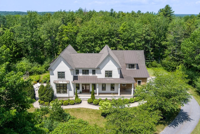 38 Fieldstone Ln, Falmouth, ME 04105 - view of front of home with a standing seam roof, a porch, a wooded view, and a metal roof