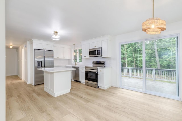 70 Whitten Rd, Kennebunk, ME 04043 - kitchen featuring stainless steel appliances, light countertops, white cabinets, light wood-type flooring, and a kitchen island