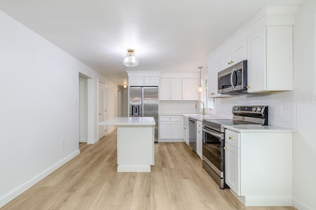70 Whitten Rd, Kennebunk, ME 04043 - kitchen with appliances with stainless steel finishes, decorative backsplash, a kitchen island, light wood-style flooring, and light countertops