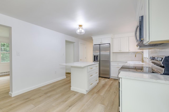 70 Whitten Rd, Kennebunk, ME 04043 - kitchen featuring appliances with stainless steel finishes, light wood-style floors, light countertops, tasteful backsplash, and a kitchen island