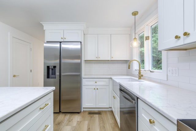 70 Whitten Rd, Kennebunk, ME 04043 - kitchen with stainless steel appliances, white cabinets, light wood-style floors, light stone counters, and backsplash