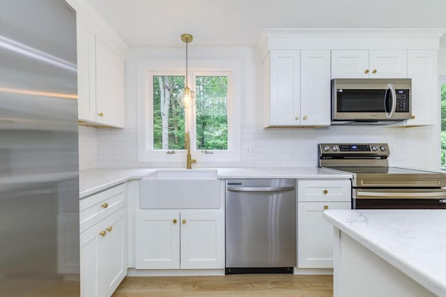 70 Whitten Rd, Kennebunk, ME 04043 - kitchen featuring appliances with stainless steel finishes, decorative backsplash, white cabinetry, and pendant lighting