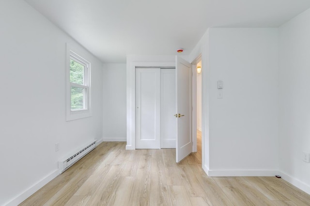 70 Whitten Rd, Kennebunk, ME 04043 - unfurnished bedroom with baseboard heating, light wood-style floors, and a closet
