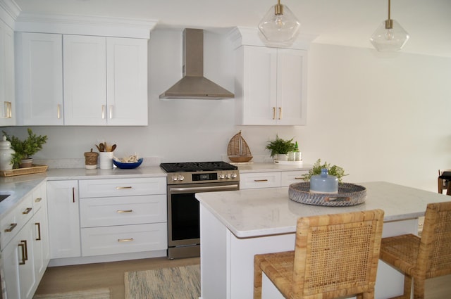 14 Salt Point Dr Unit 19, Old Orchard Beach, ME 04064 - kitchen featuring stainless steel gas range, wall chimney exhaust hood, a breakfast bar, and white cabinets