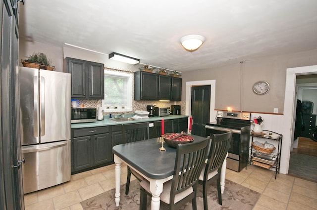 198 3rd St, Bangor, ME 04401 - kitchen with stainless steel appliances, light tile patterned floors, backsplash, a wainscoted wall, and light countertops