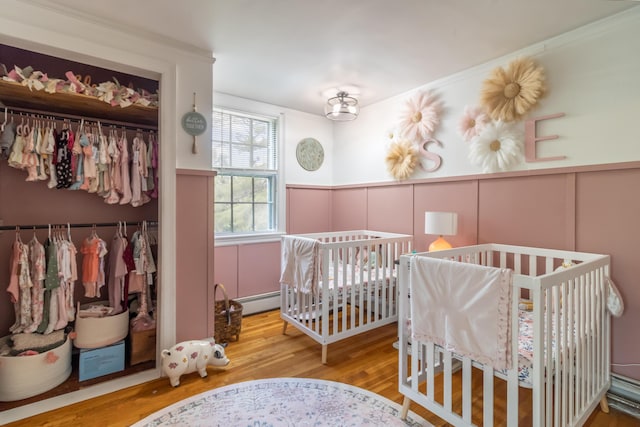 166 Franklin St, Bucksport, ME 04416 - bedroom with a closet, a decorative wall, wood finished floors, wainscoting, and baseboard heating