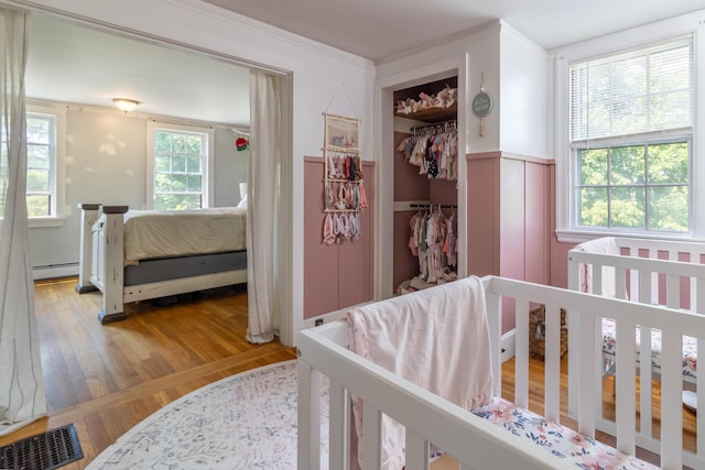 166 Franklin St, Bucksport, ME 04416 - bedroom with wood finished floors, a wainscoted wall, a baseboard heating unit, crown molding, and a closet