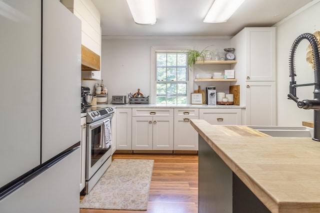 166 Franklin St, Bucksport, ME 04416 - kitchen with freestanding refrigerator, stainless steel range with electric cooktop, light wood-style flooring, white cabinets, and ornamental molding